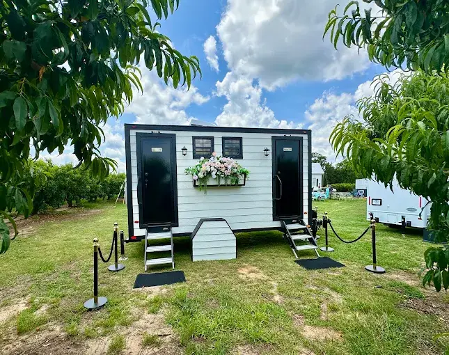 Cottage-style luxury restroom trailer at an outdoor South Carolina wedding, illustrating a wedding restroom rental checklist.