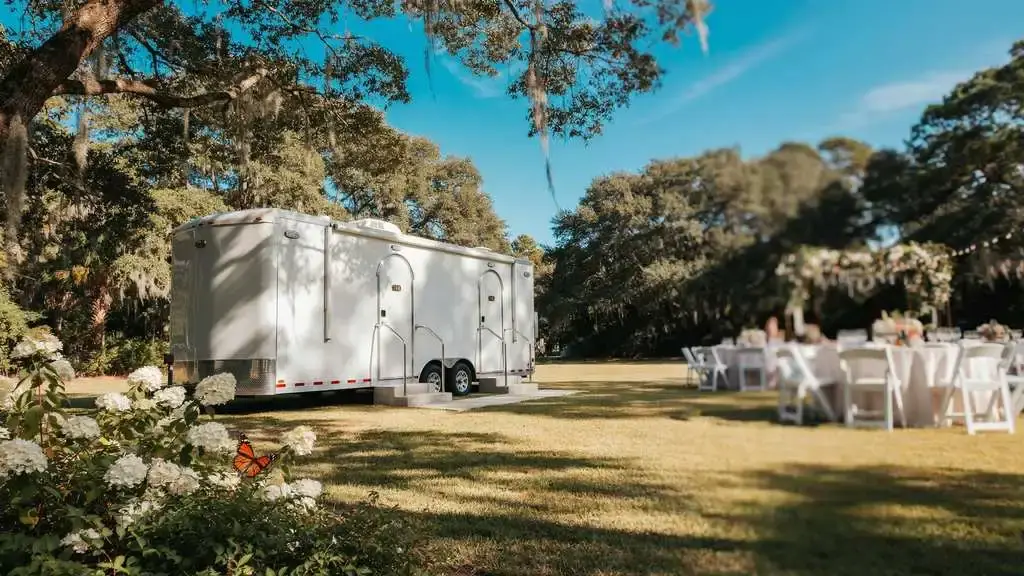 Climate-controlled restroom trailer placed in partial shade at an outdoor summer event in South Carolina.